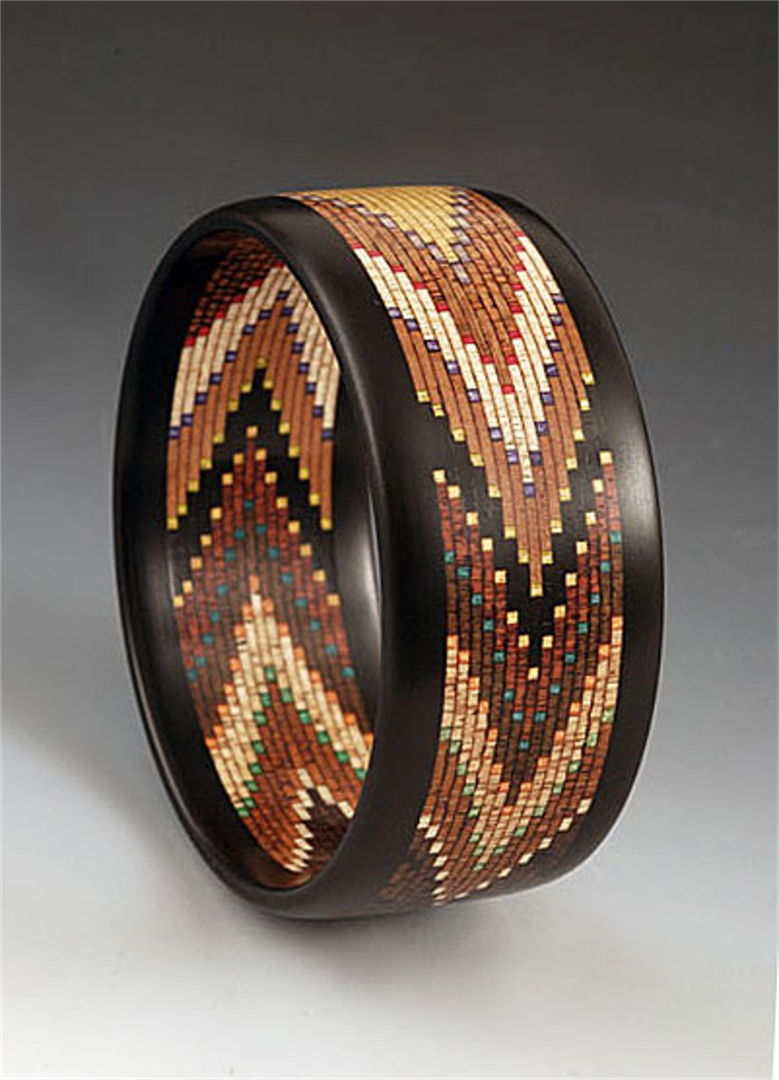 This bracelet has 12 different specie of wood in it all natural colors and artist dyed maple veneer. There are 600 pieces of wood in it with Ebony edges.