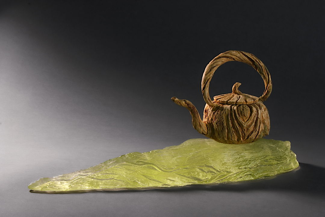 Hand-carved ceramic trompe l'oeil teapot on cast glass stand.