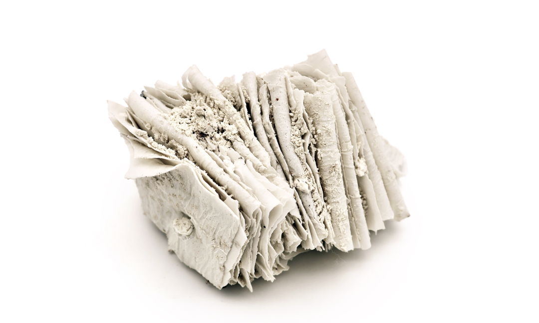 Porcelain are folded and compressed  with white clay powder packed between the layers before firing. The powder locks into the seams  preserving a soft  fossil-like texture so the form reads like a small bundle of pages or strata. A quiet study in touch  fragility  and time.