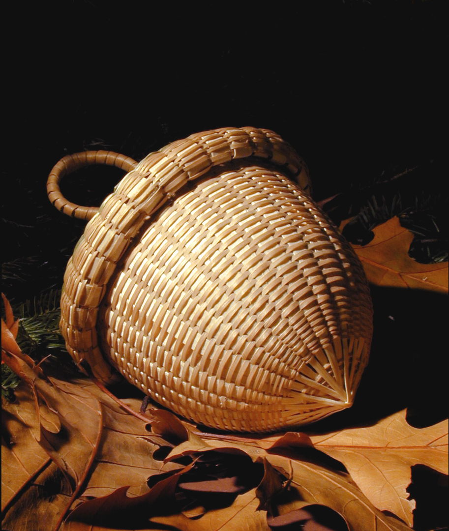 Acorn sweetgrass basket with brown ash rims and handles.