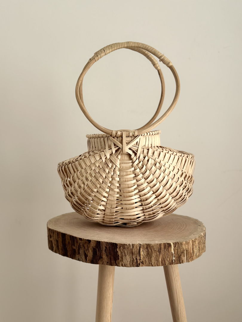 basket purse with light wood weave and full circle handles.