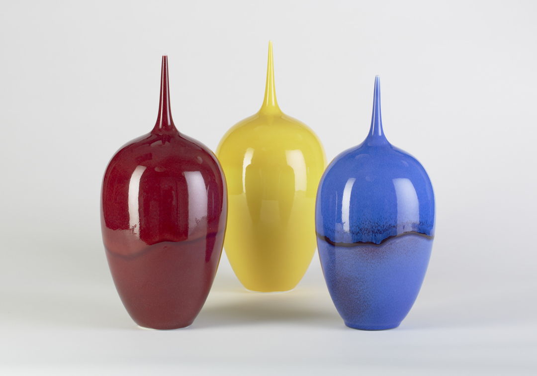 three vases with skinny necks in yellow, blue, and red