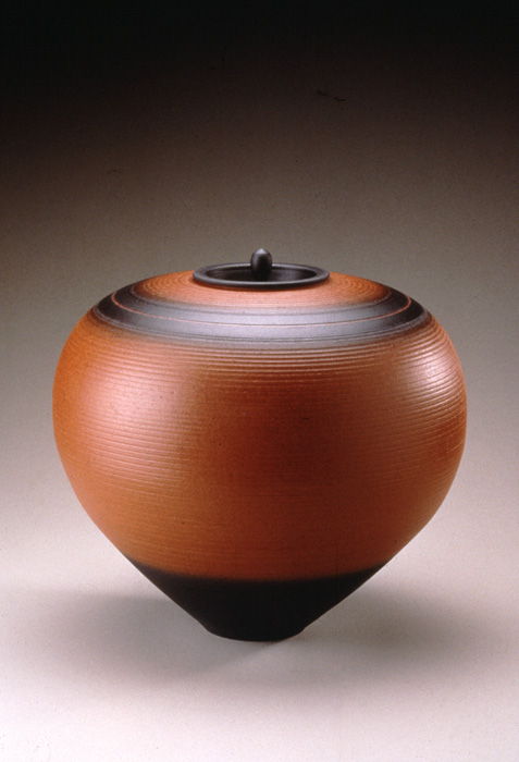 Thrown brown terracotta pot with black accents and small lid.