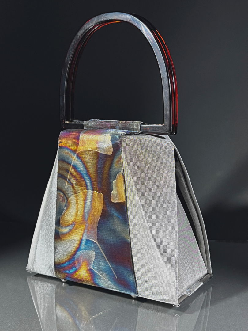 Evening handbag made of stainless steel mesh  decorated with the illusion foil. Adjustable handle made of aircraft cable