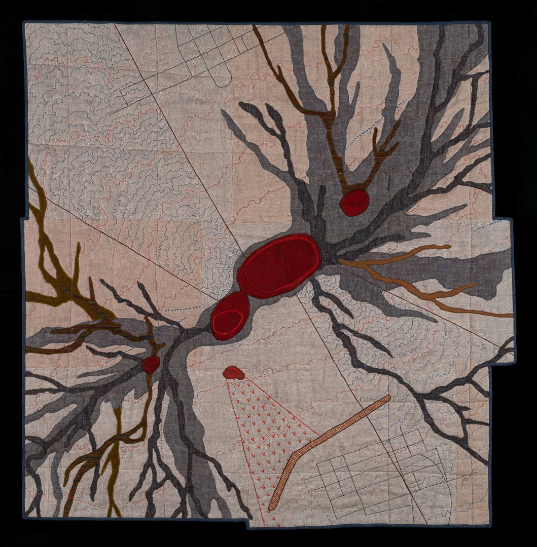 appliqued and quilted aeriel view of a volcano with various map survey details such as elevation markers