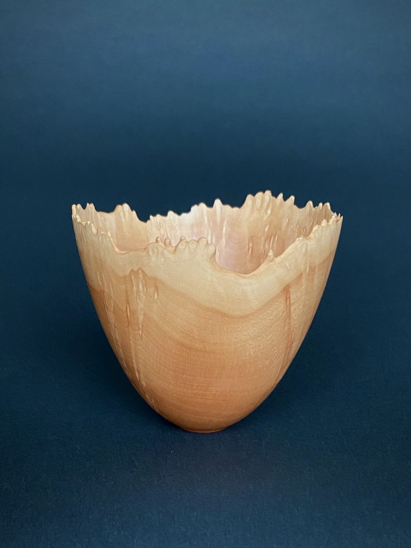 Gentle but spiky burl points dress the rim of this small vase. Color changes follow the natural rim and the burled sides shimmer. All adds to a reaching quality. The shape is a pleasure to hold.