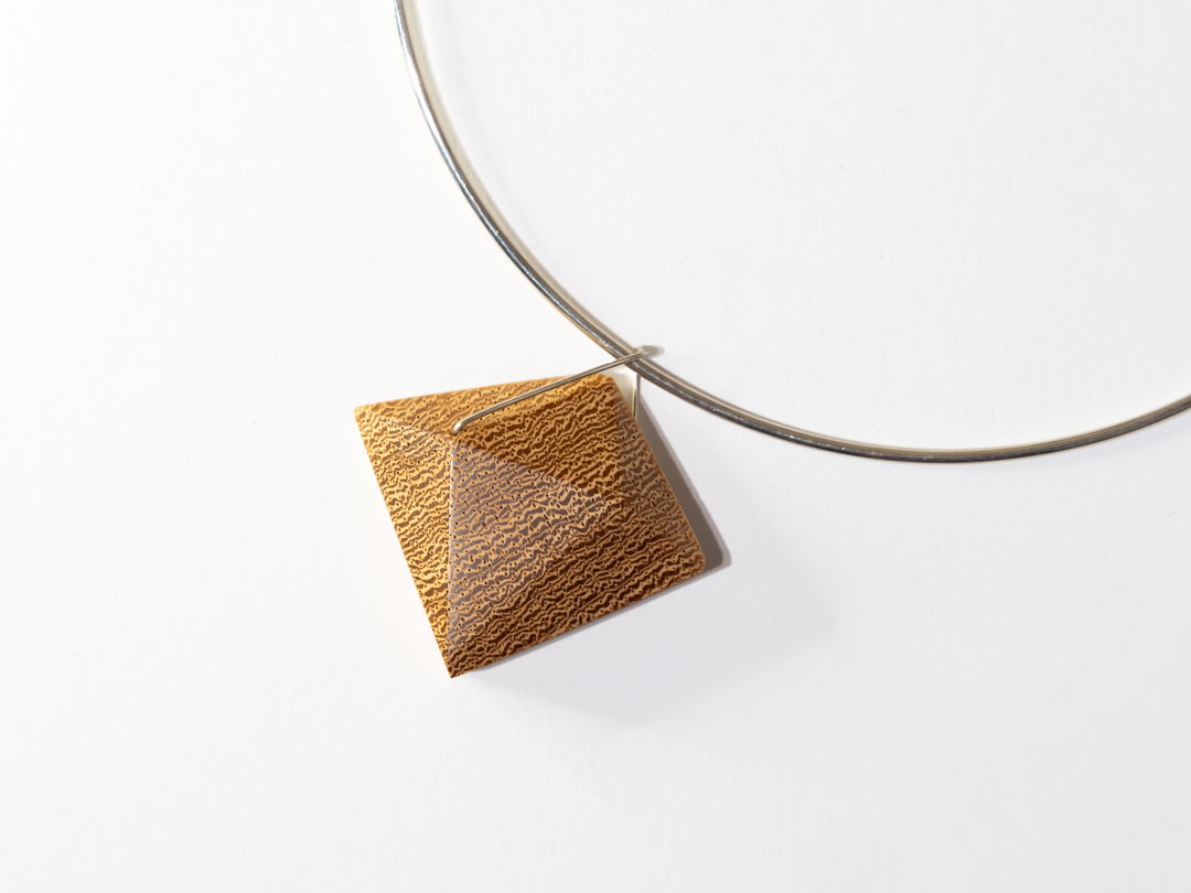 Lati Wood hand shaped and polished with Argentium Silver hoop detail on Sterling Silver Collar. A locking system is employed to bond the metal and wood. A keyhole system is drilled within the wood and the metal is knurled before epoxying wood and metal together.