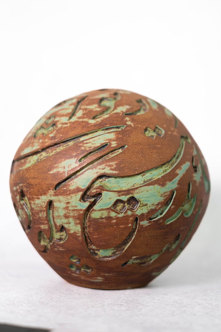 round vase with swirls of brown and green and inscription