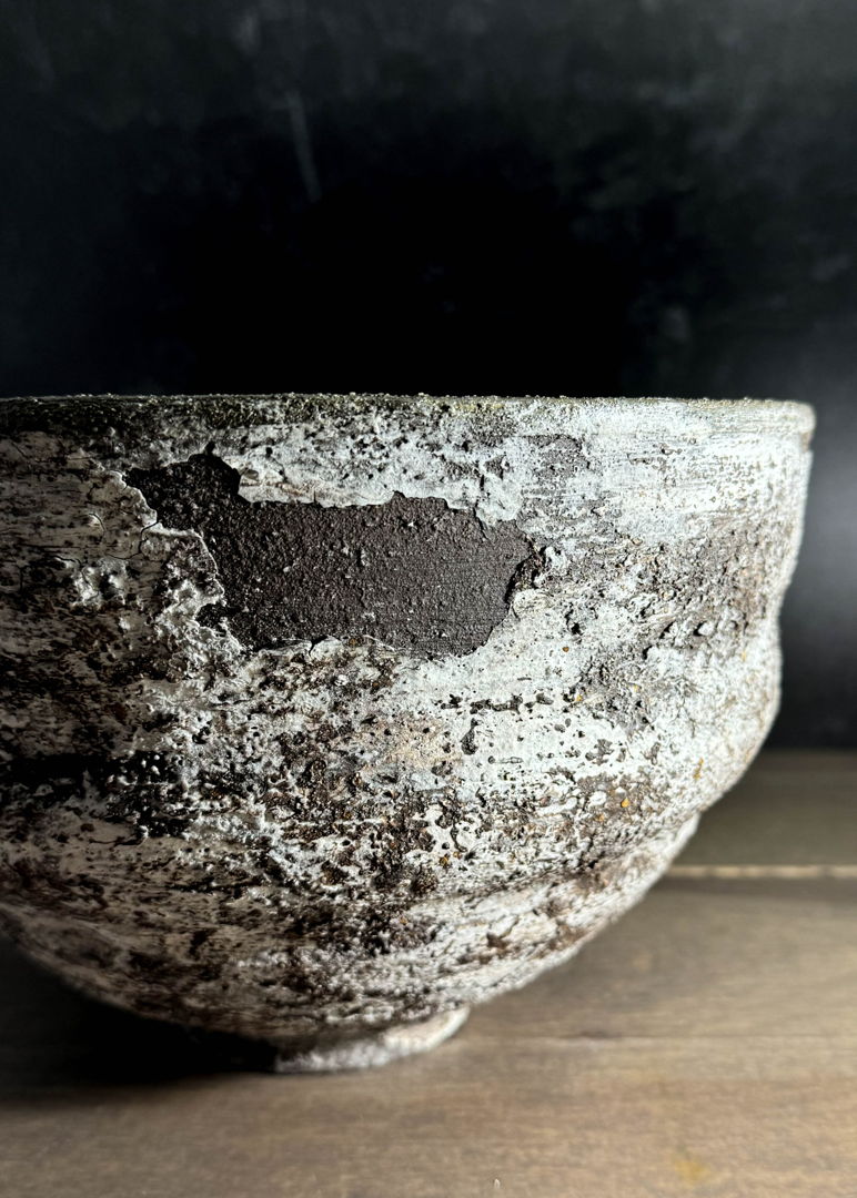 The Volcanic fields bowl is thrown from a dark clay body  altered with a spiral design  and decorated with several layers of heavily textured slip in a process designed to allow the slip to crackle and in some areas release to reveal bare clay. The piece has been lovingly sanded to its final finish. Inspired by the moss and lichen covered lava fields of Iceland.