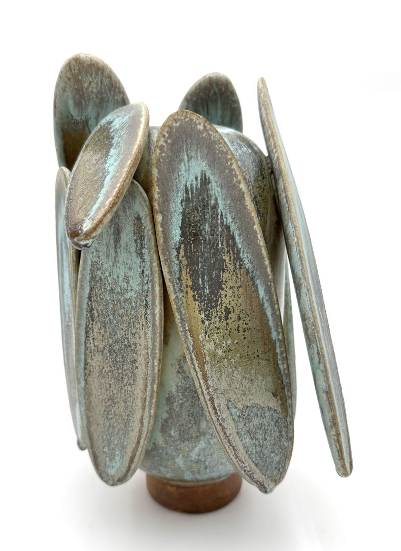 Camouflage and form meet in this Butterfly Lichen piece. Soda fired with multiple crystalizing glazes that break from browns to grays to turquoise to black. Colors change with each view on this tall ovoid form with large extensions.