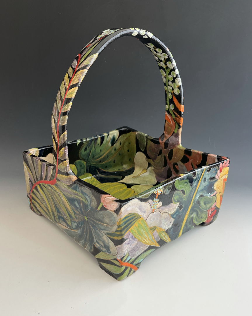 Basket made with a combination of hand-building and wheel-throwing techniques with painterly glaze and under glaze decoration of leaves and flowers on a dark background.