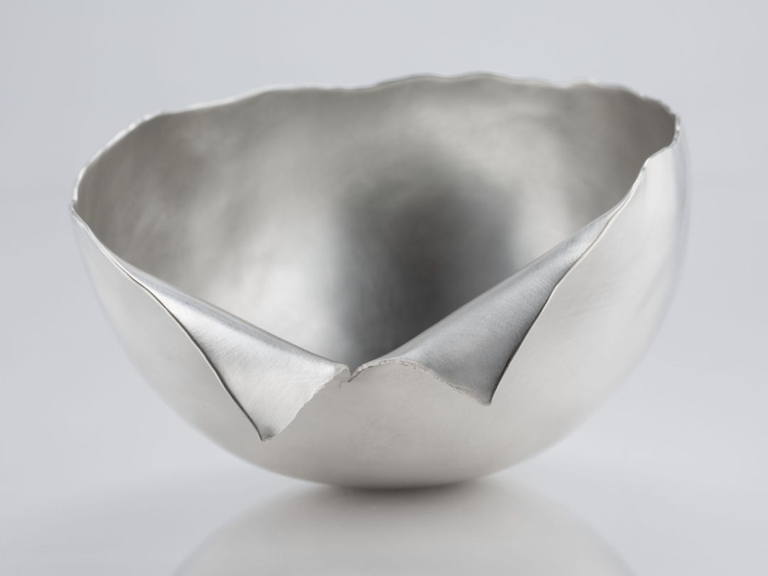 I took a flat sheet of silver and hammered it up into a three dimensional form using traditional silversmithing techniques. Sometimes during this process the metal begin to tear. I incorporated those tears into the form rather than cutting them out or repairing them.