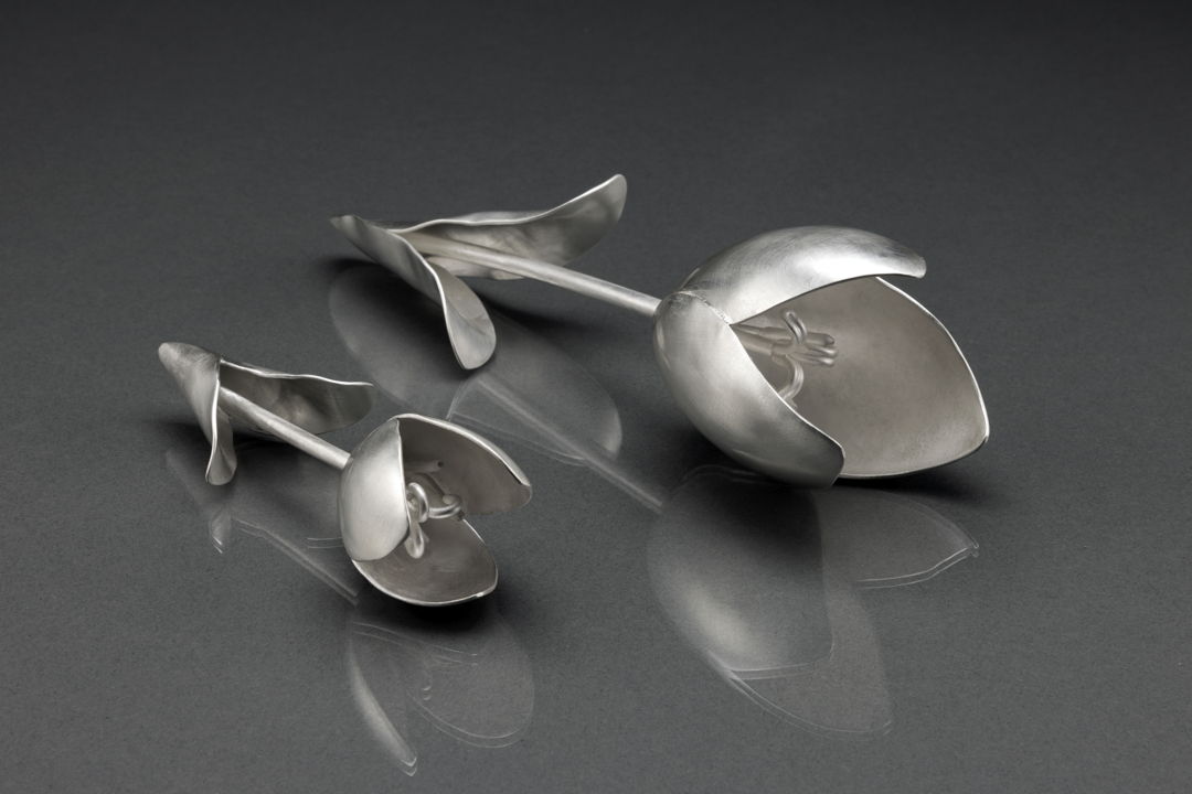 Each tulip is hand fabricated from flat sheets of sterling silver. Each pedal was hammered  curved  and shaped. All the parts were then soldered together. This resulted in the construction of each form becoming like three dimensional jigsaw puzzles. The flowers were then sanded to a silky  satin finish. I wanted to make beautiful  sculptural objects based on tulips. They're soft  minimal  and occupy space. Small: 6" long. Large: 9" long.