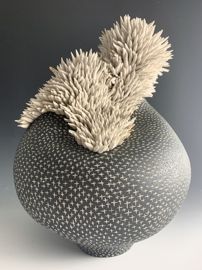 Porcelain vessel with carved crosses topped with clusters of sea anenome-like tenticles with accents of  gold luster