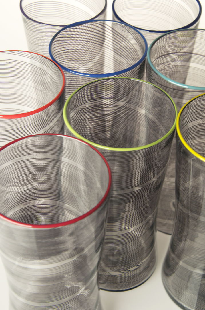Clear blown glass vessels with black rods of clored glass or canes fused into the surface  blown and twisted. Each piece is finished with a colored glass lip.
