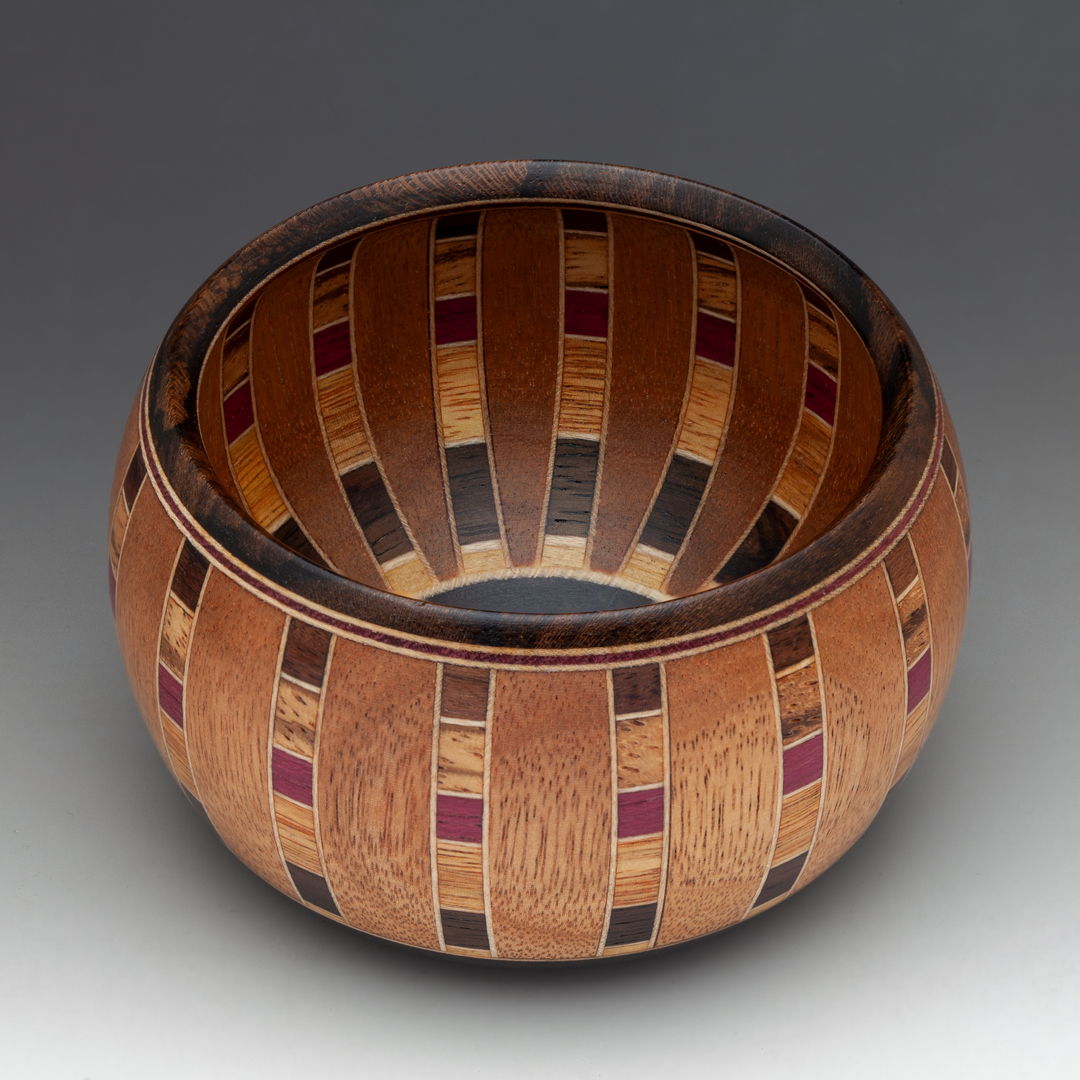 Chartres Anemone is a small intricate vessel of the Chartres series. Vertical stave construction with Honduras Mahogany and Maple veneer. 6 specie of wood and 300 individual pieces  Ebony base and Rim