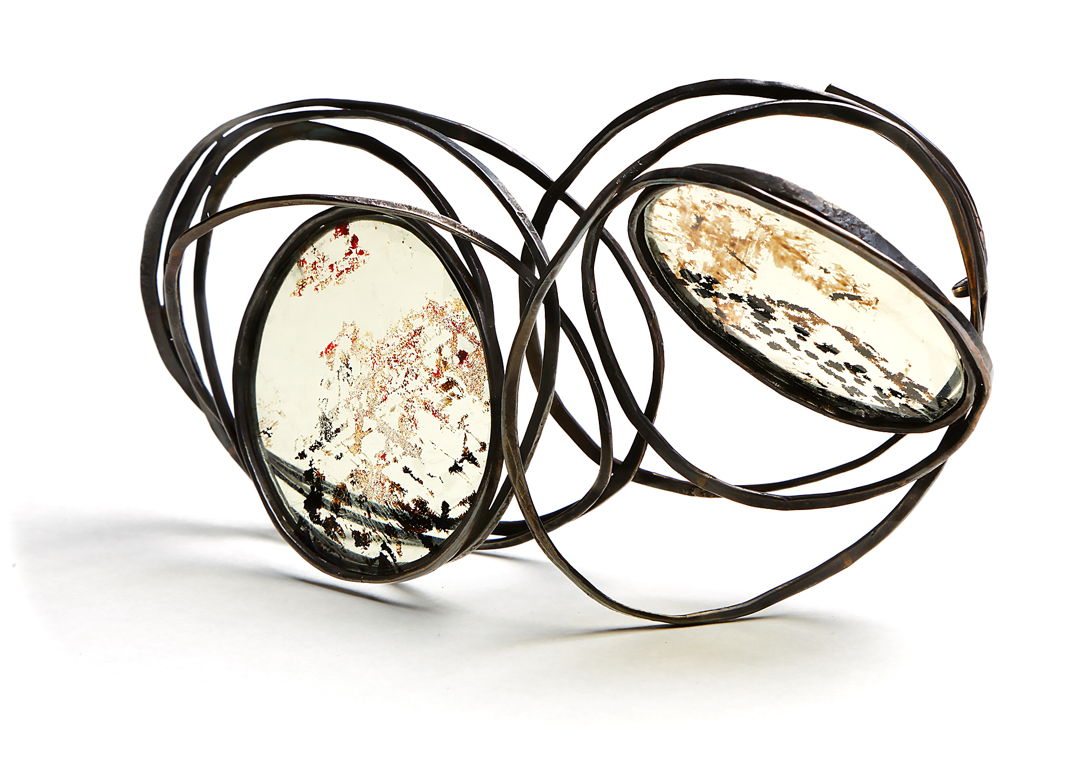 One of a Kind Brooch A chain is made of forged bronze wire. The chain is manipulated to create a 3 dimensional structure showing the union and rhythm of variation. Stove mica is set to highlight the forms and self.