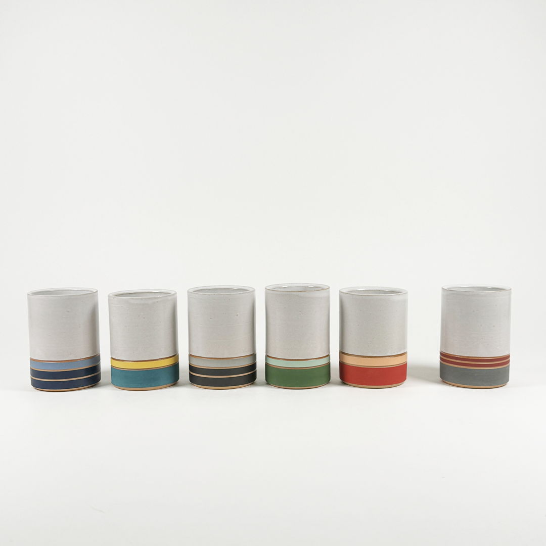 Wheel-thrown stoneware cups with satin white glaze and colorful carved underglaze stripes.