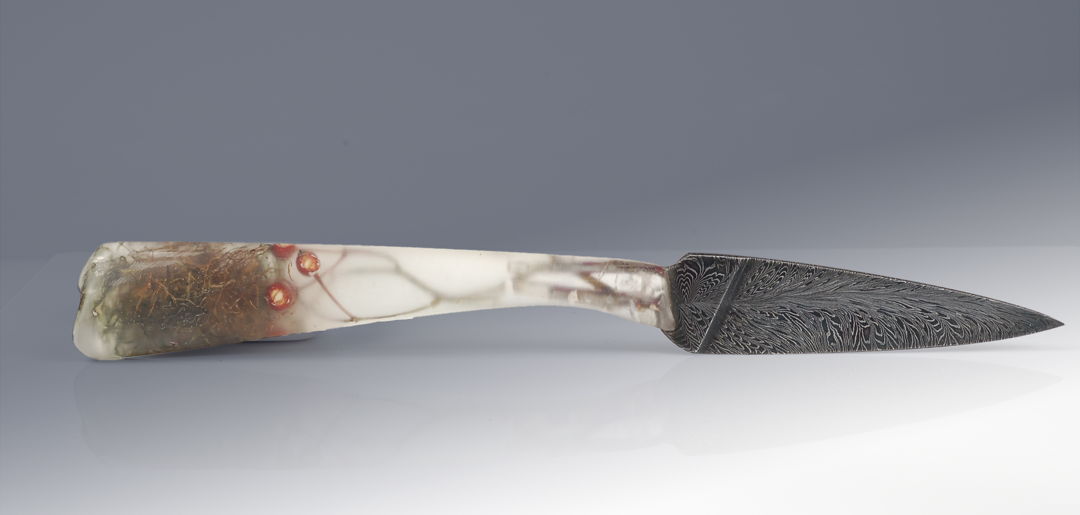 Moss  branches  seeds frozen in a resin handle hold a feather pattern blade of house made Damascus steel