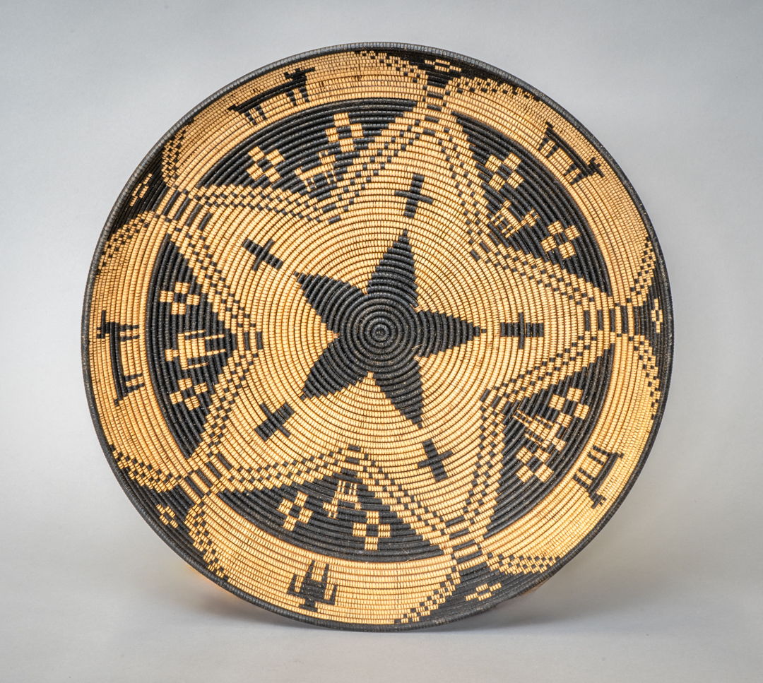 A wood basket tray made on a wood lathe. Wood is then embellished with India Ink and a burning pen.