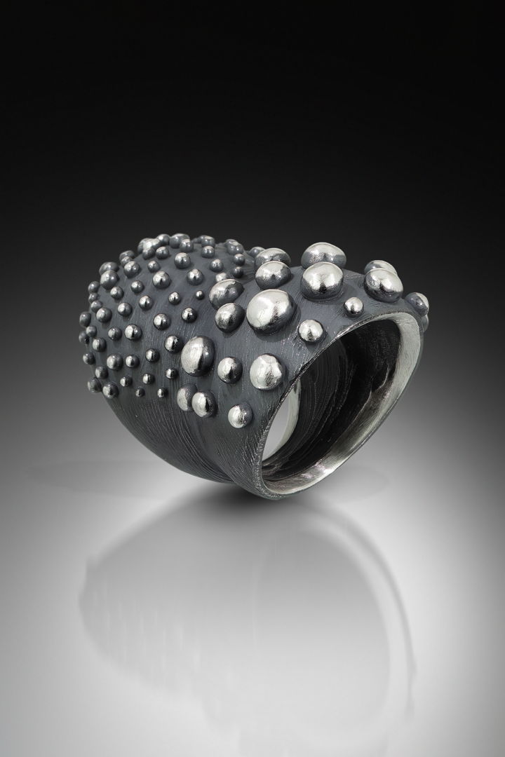 carved double domed ring in oxidized silver with varying sizes of bumpys.