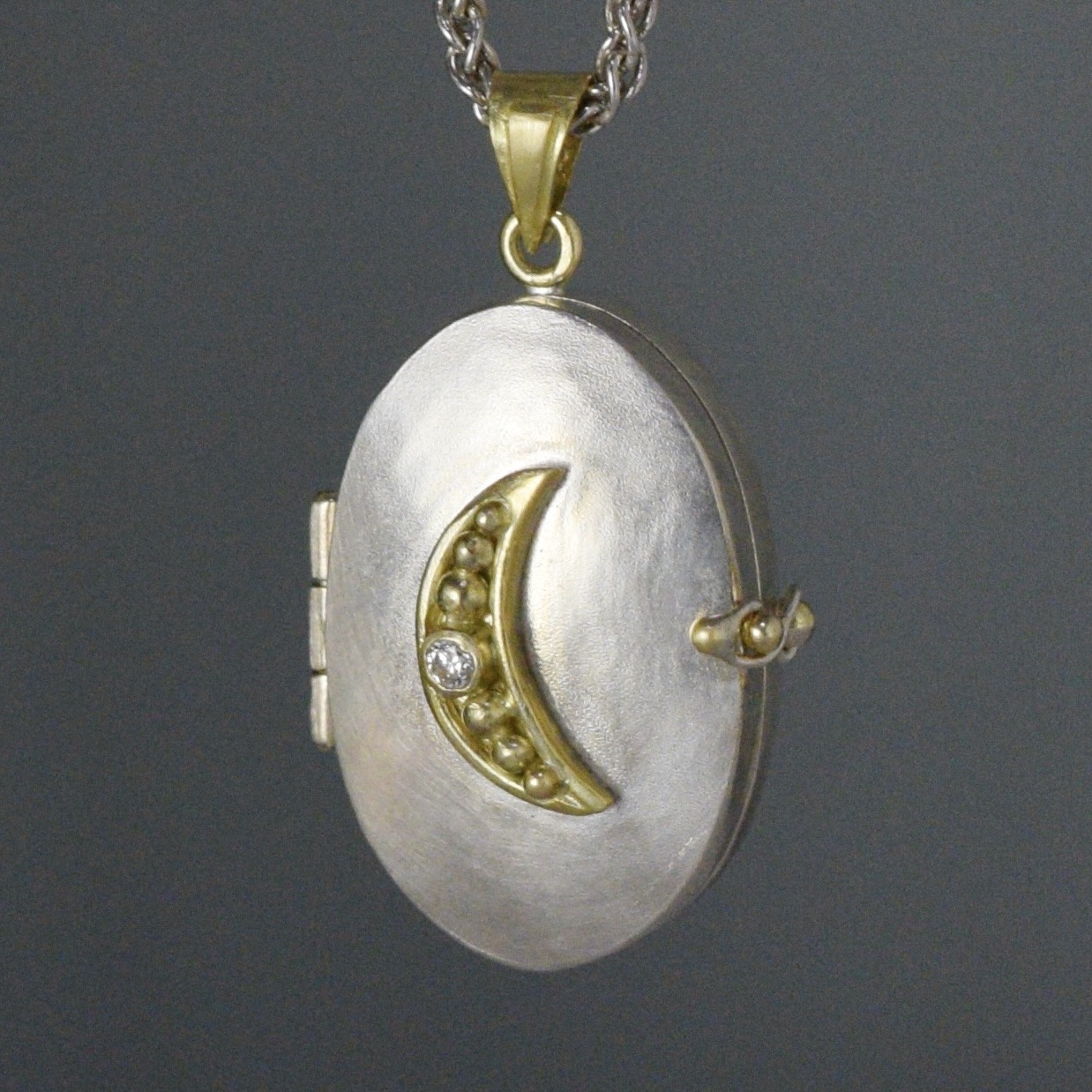 silver and gold charm with crescent moon