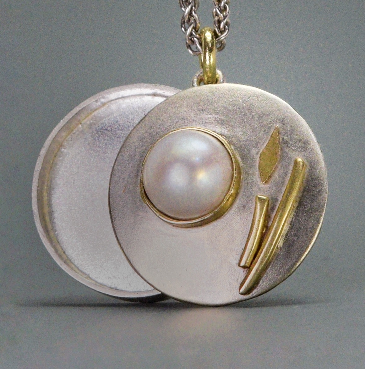 round silver, gold, and white charm