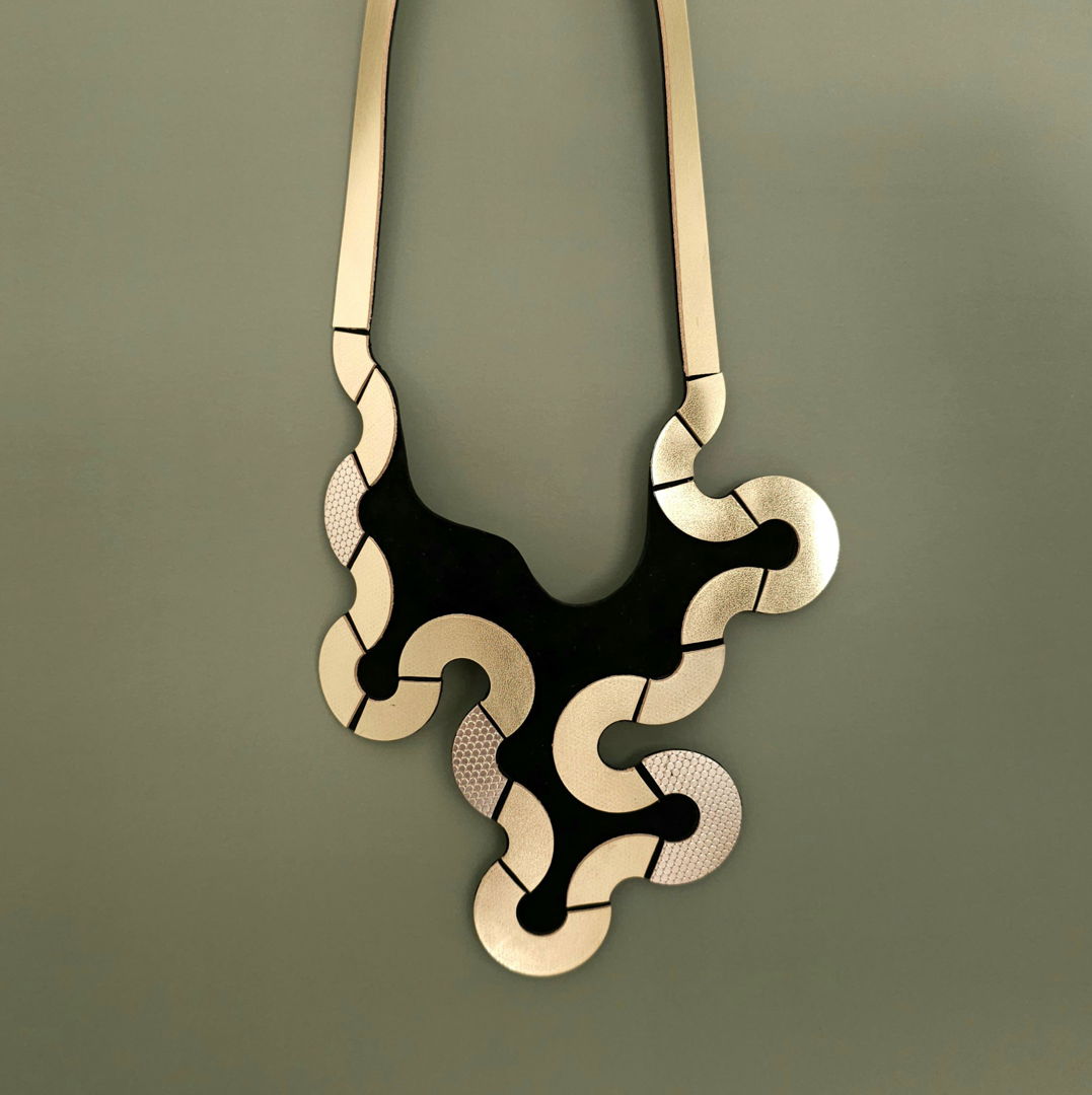 Inspired from trails of animals on the sand  crafted with Gold metallic quality leather  this sculptural piece plays with puzzle-like patterns. Easy to wear magnetic clasp.