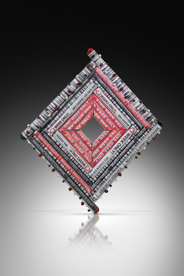 Assorted portions of Expired Manufacturer Coupons including expiration dates and UPC Bar Codes are hand-formed into beads and stitched together with Swarovski Crystal beads and Japanese glass seed beads into the form of a brooch. 2021
