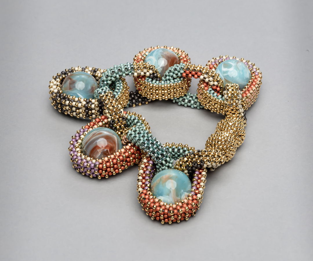 Bracelet with magnetic closure part of the collection Pods. handwoven with fine 24K gold plated and Toho duracoat seed beads. Vintage marbled lucite spheres are nestled in the bead mesh in place of gems. Ongoing collection  limited edition available in various color combinations.