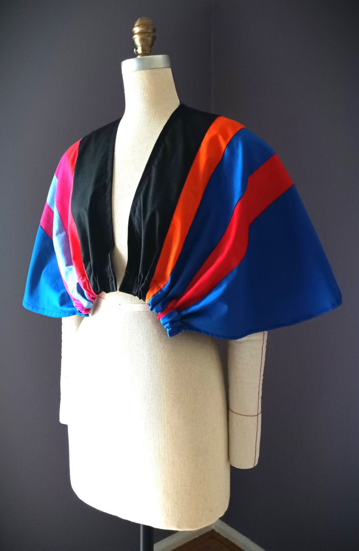 The Bolero Geometric Winged Cape embodies movement  transformation  and artistry in wearable form. Constructed from fine QUILTED cotton fabrics  each panel is precisely cut in varying colors and widths  creating a vibrant geometric interplay across the shoulders. A showcase of artisanal craftsmanship  it bridges contemporary couture with timeless artistry.