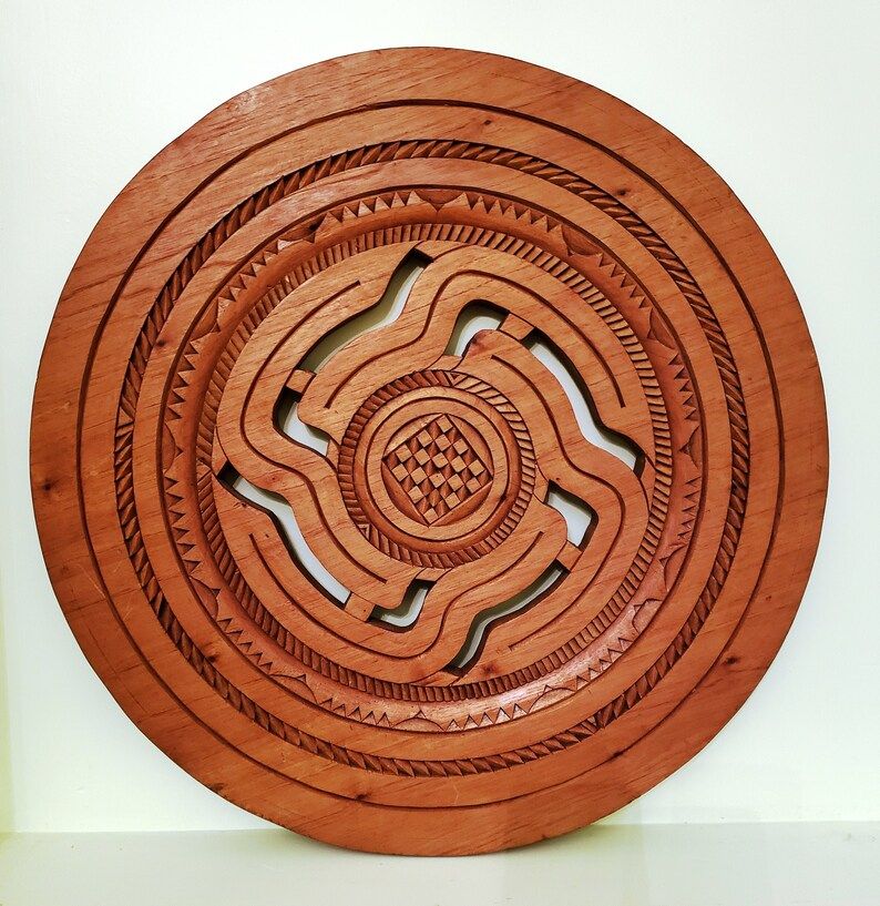 Wall art carved of tropical cedar: the circle of cutouts represent the passage of life and the carving tradition from one generation to another