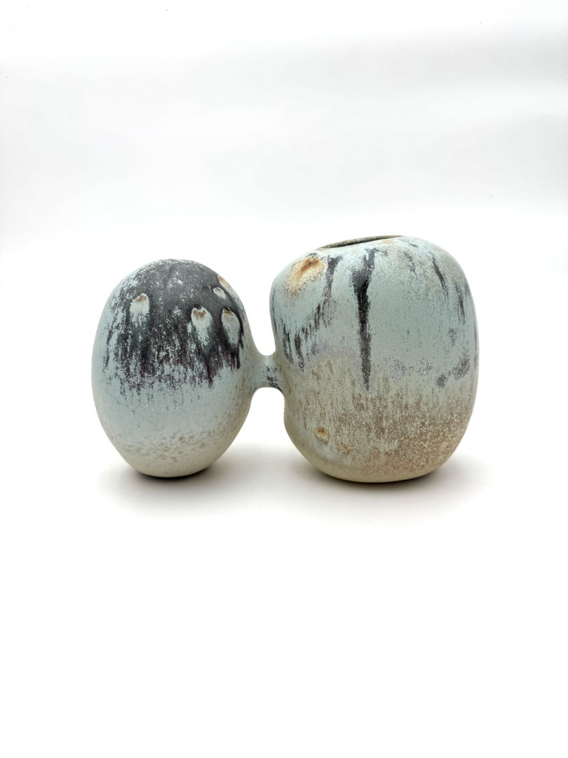 Imagined relationship between rock forms. Double shaped vessel with rock like glaze coloration that breaks from pale browns to navy blue. Soda fired piece with multiple glazes. Stoneware and glaze.