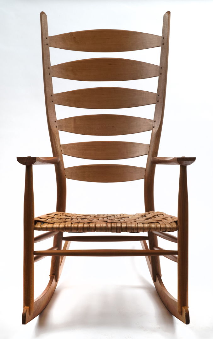 Walnut rocking chair featuring steam bent components  hand-shaped surfaces and a woven hickory bark seat. Oil and wax finish.