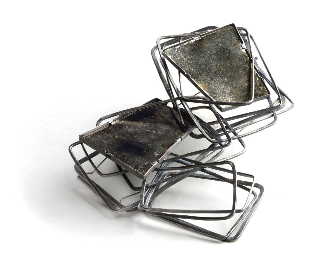One of a Kind Brooch A chain is created with forged sterling silver rectangles. Together these links create a platform to set the black mica. The 3 dimensional configuration gives the illusion of stepping into ones place.