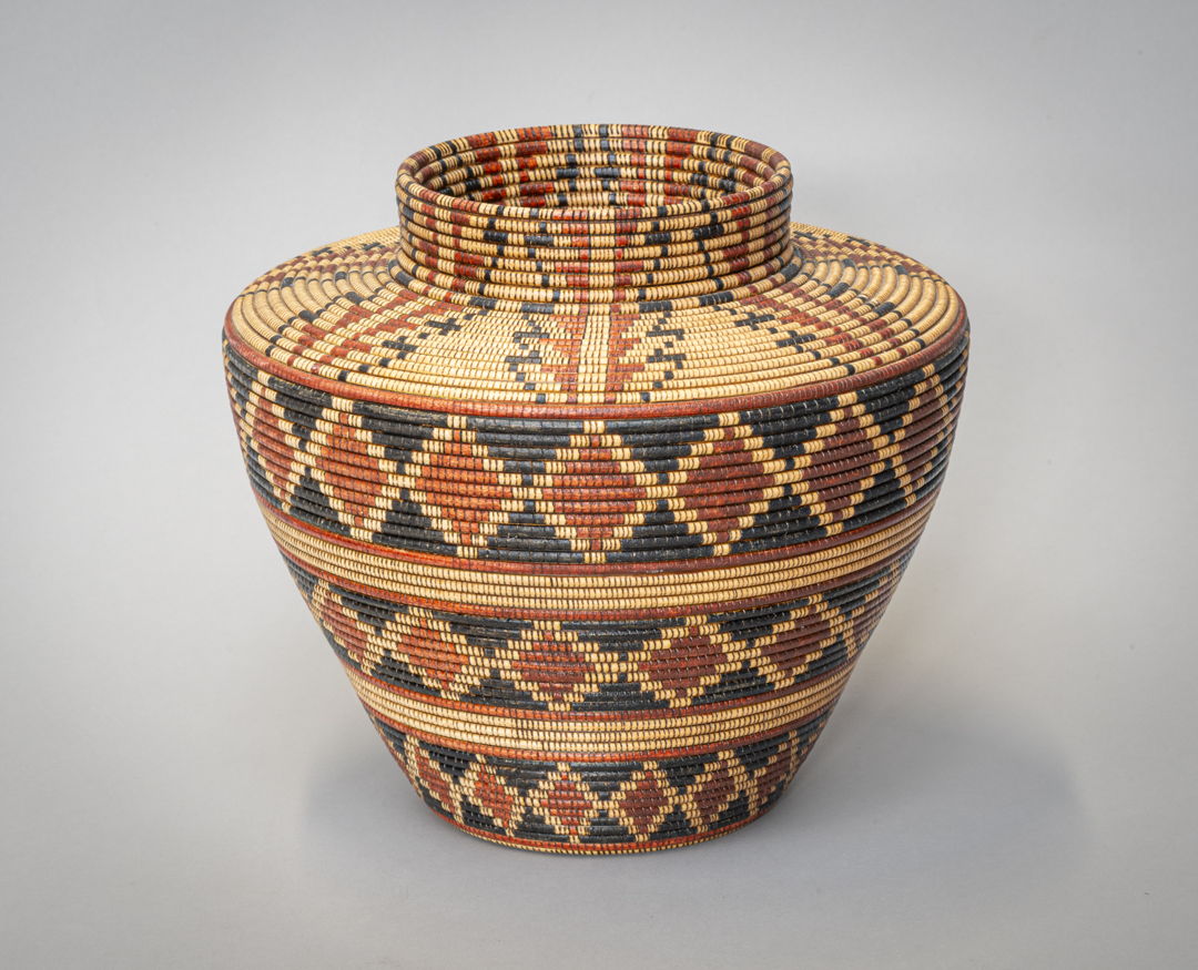 A wood basket made to resemble a Yokuts Bottleneck basket. The piece is turned on a wood lathe  then embellished with India Ink and a burning pen.