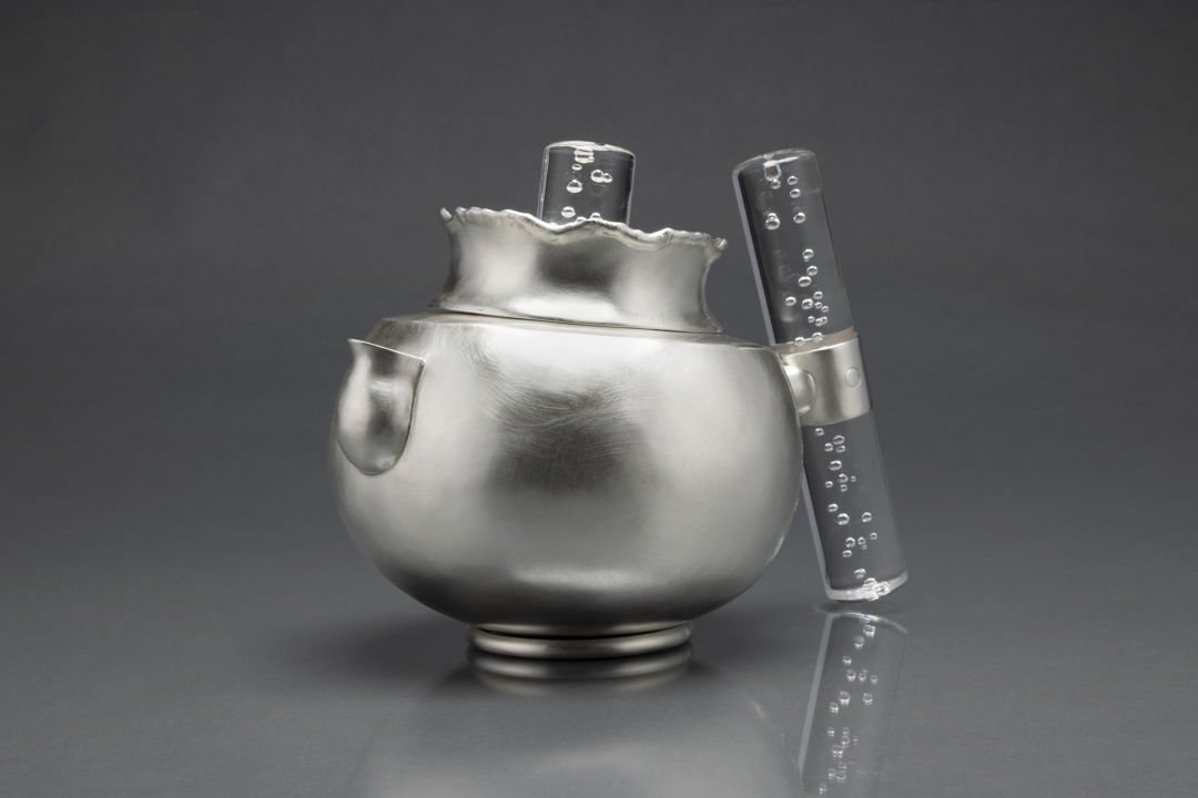 A fully functional sterling silver teapot. The piece is all hand fabricated from flat sheets of sterling silver. The form was hammered from a flat sheet of silver up into a three dimensional form. The lid and handle was fabricated from silver sheet as well. The handle and finial are acrylic.