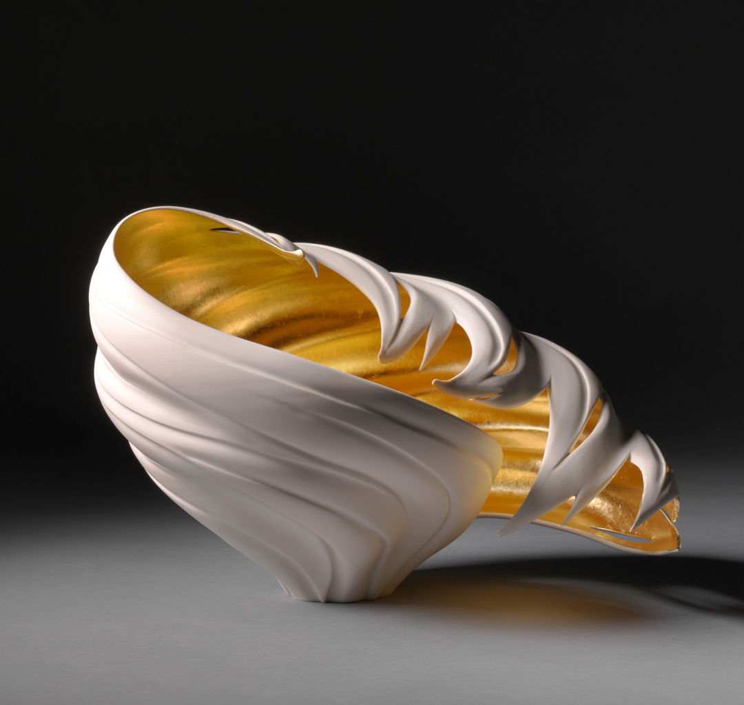 Porcelain that has been carved. Interior is gold gilded.