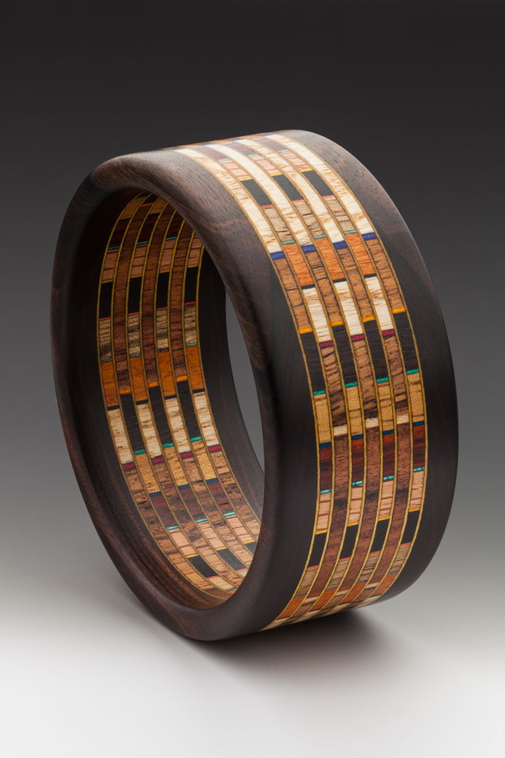 12 different hardwood specie of sustainably harvested wood and artist dyed Maple veneer. Mum Ebony edges from Laos  The wooden fabric design has 300 individual pieces of wood.