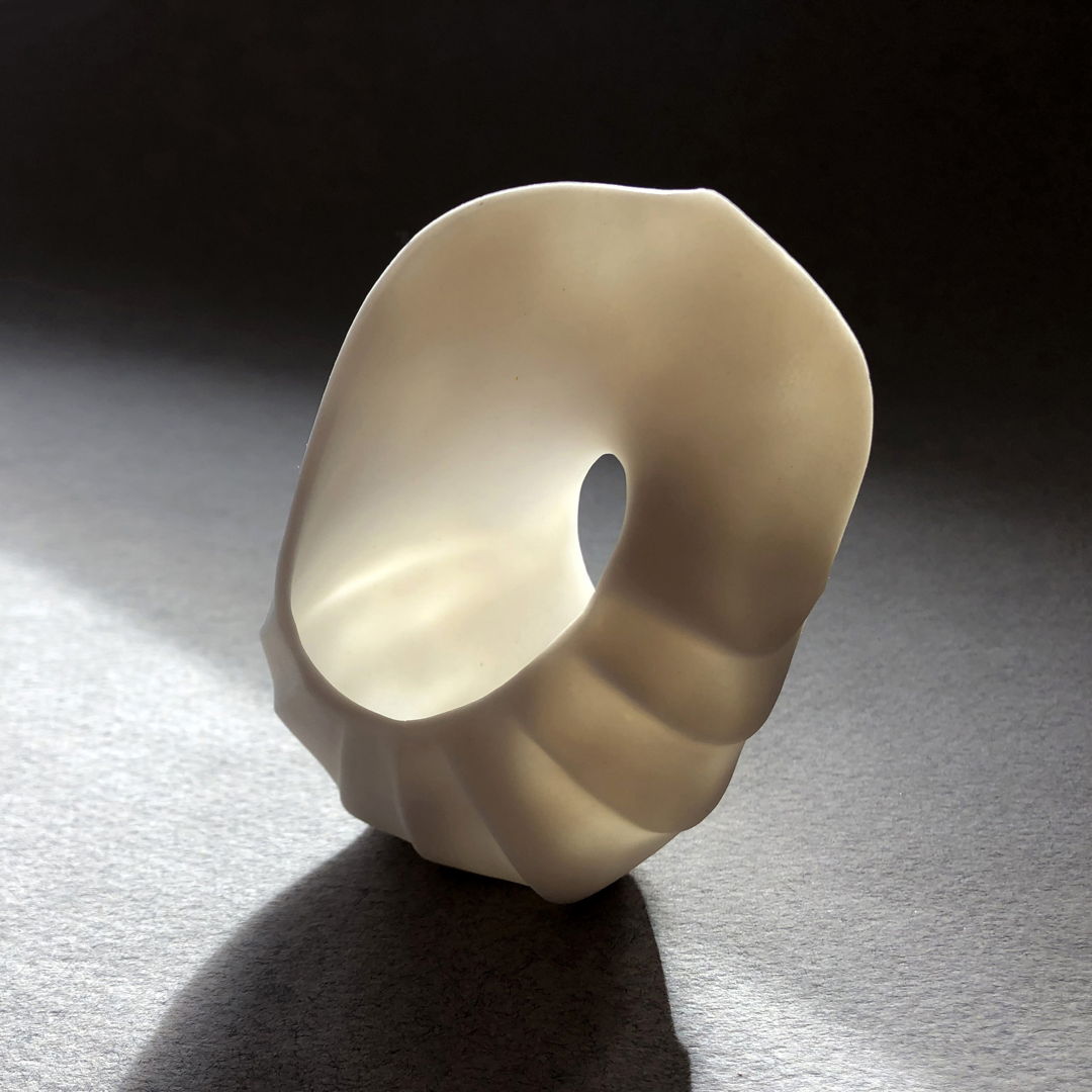 This high fired mobius porcelain piece was created by pinching  cutting  handbuilding  and carving. It has an unglazed surface.