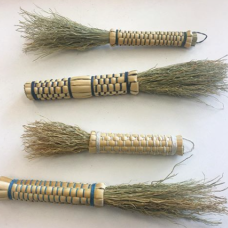 A collection of four plaited broomcorn brushes.