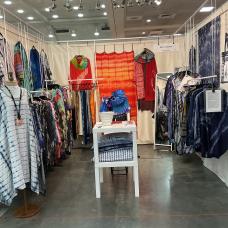 Booth layout with collection of cashmere shawls  pleated silk garments and accessories  and cotton Personalized Shirts.