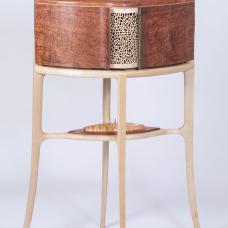 This delicate walk-about tea cabinet has matching recurved doors that provide a peek at what lies within. The rear of the cabinet is identical to the front. The piece features waterfall bubinga burl  carved and sculpted maple  an interior carousel revealing sterling silver  mother of pearl and micro-mosaic detail  and 10 drawers featuring floral inlays using mother of pearl and turquoise.