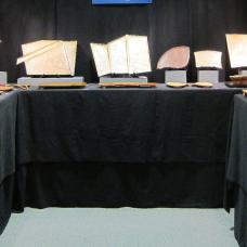 Booth with tables in a u shape covered in a black table cloth with the items on display