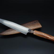 Forged from more than fifty bars of bloomery steel  this chef knife's 8&amp;quot; blade is decorated with the water ripples and herringbone twists that adorned ancient sword blades. The subtly patterned blade is mounted in a handle carved from stabilized walnut and apple wood  and can be sheathed in a walnut scabbard.
