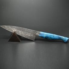 An everyday kitchen workhorse  this 7" chef knife's blade is handforged from folded nickel and carbon Damascus steel  mounted on a dyed and stabilized box elder maple handle.