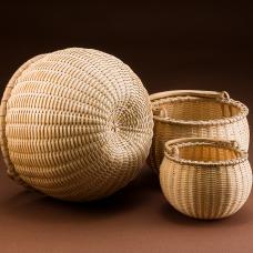 Nest of three swing handle baskets. Woven of pounded and hand-scraped brown ash splint with hand split  carved  and green bent.