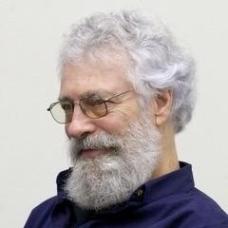 Side view of a man with greying hair, beard, mustache and glasses