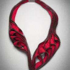 Captivating  one of a kind necklace made from zippers. Fervor uses a red zipper with black metal teeth to create a unique shape that references a heart-shape crossed with the shape of the human lungs. Necklace is hand-stitched and machine-stitched. Fastens with metal clasp in back.