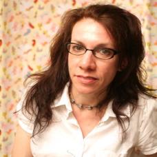 Female with brown wavy hair past her shoulders with glasses in a white short sleeve button up top